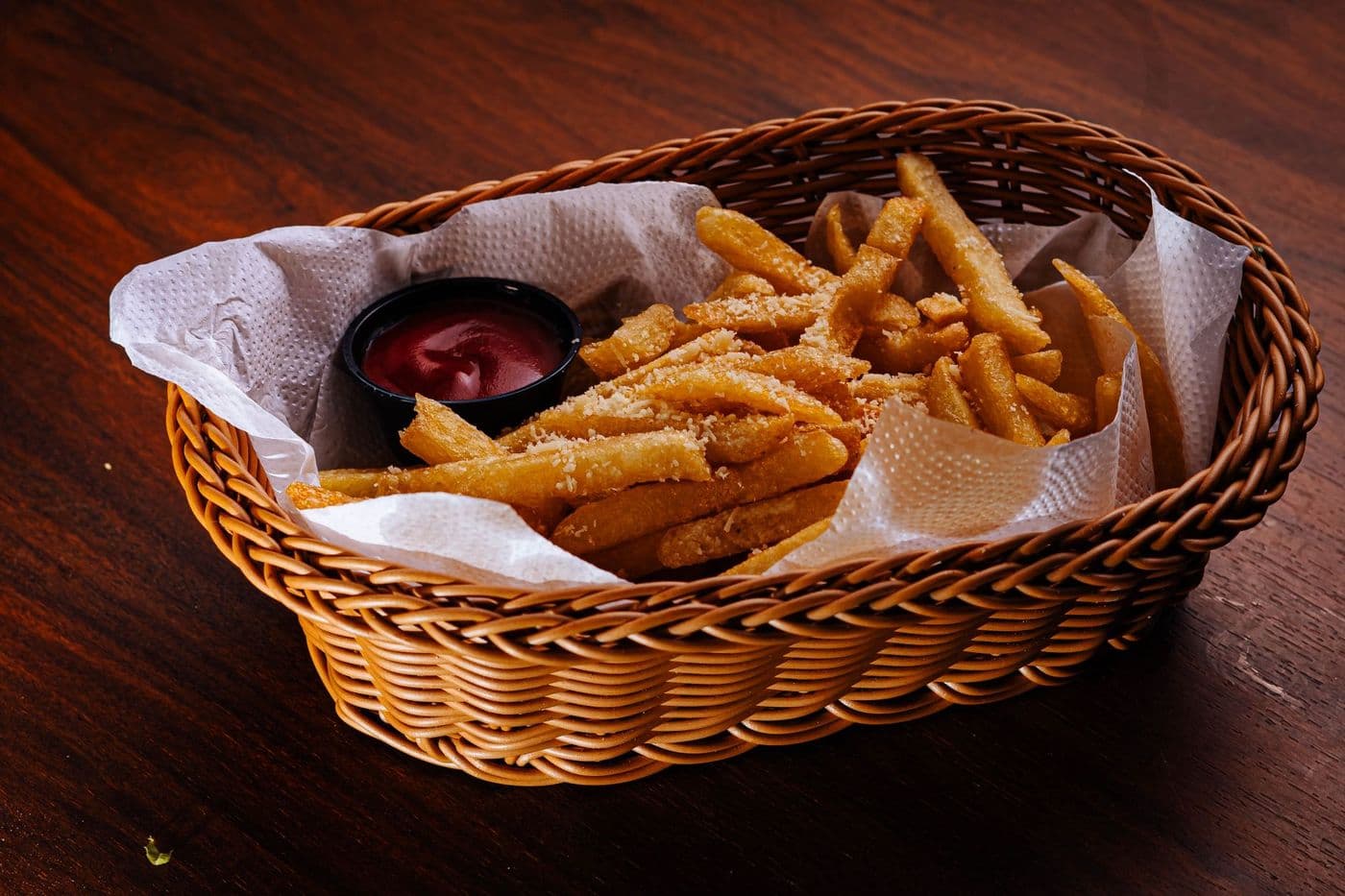 Delicious French fries with parmesan served in a basket with ketchup dip.